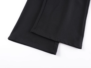 Detail view showing hem stitching and premium heavy fabric texture of black wide-leg pants