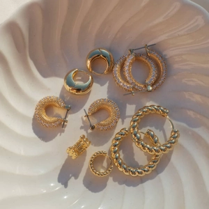 Close-up of 18k gold plated stainless steel hoop earrings with white cubic zirconia in shell dish