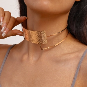 Detailed close-up of a golden wide metallic choker with a textured hammered finish on a neck