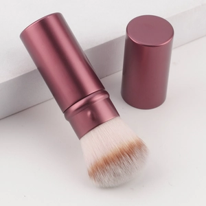 Portable plum purple retractable makeup brush with dust cap on minimalist white stones
