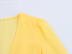 Close-up of yellow V-neck dress featuring delicate lace trim and size S label detail