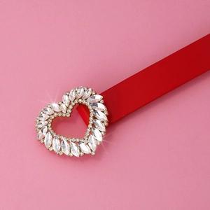 Close-up of a red leather belt with a sparkling heart-shaped buckle inlaid with crystals