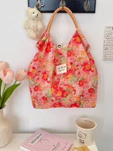 Floral canvas tote bag with orange checkered handles and vintage aesthetic displayed on a wall