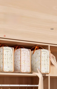 Stack of thick transparent PVC storage bags with orange trim on wooden closet shelves