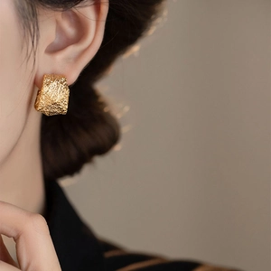 Golden textured C-shaped earrings with vintage crumpled metal finish worn by model