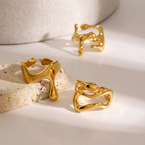 Three pieces of fluid gold stainless steel rings on a natural stone background