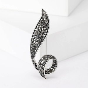 Elegant vintage gunmetal leaf brooch with dark grey rhinestones on a white pedestal