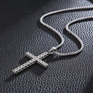 Macro detail of silver stainless steel cross pendant with woven texture on leather