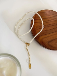 Detail of freshwater pearl necklace featuring a golden lobster clasp and extension chain