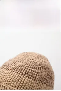 Dettaglio del cappello in maglia marrone chiaro con trama spessa e fodera termica calda