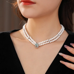 Détail d'un collier de perles à double rang avec pendentif ovale bleu et petits diamants