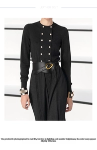 Detail of a wide black leather belt featuring a modern golden triangle metal buckle for women