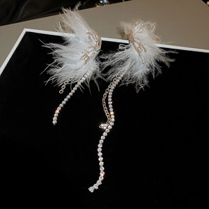 Detailed macro view of white feather tassel earrings with sparkling rhinestone chains
