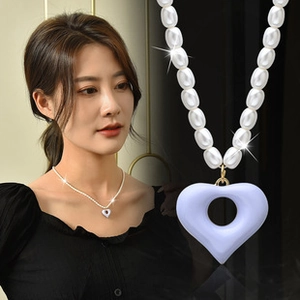 Detail of a versatile necklace featuring white pearls and a purple heart pendant charm