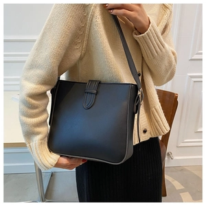 Detailed view of a black textured shoulder bucket bag worn by a model in casual setting