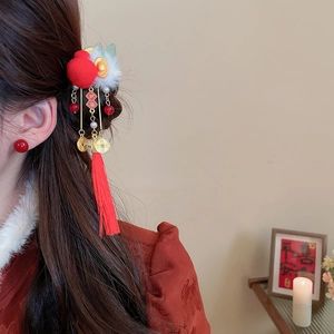 Detail of red pompom hair clip with golden charms and festive tassels on model
