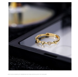 Detail of gold heart ring with pavé cubic zirconia on black mirror surface