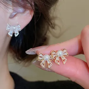 Elegant bow-shaped pearl earrings with sparkling zircon crystals in vintage gold finish