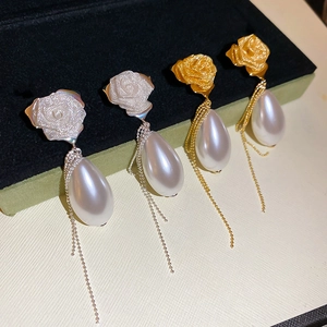 Macro detail of French style rose stud earrings with pearl drop and long metal tassels