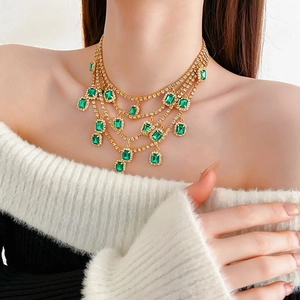 Detail of layered gold emerald necklace with diamond-set tassels on a model