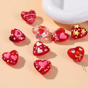 Macro view of red heart-shaped glass beads with colorful star and dot patterns