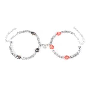 Close-up of magnetic heart clasp connecting silver Cuban link couple bracelets