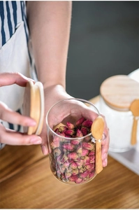 Close-up of glass storage jar with bamboo lid and spoon filled with dried rose buds