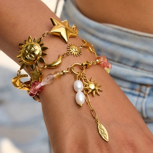 Detail of bohemian gold star and moon layered bracelets with pearls and amber stones