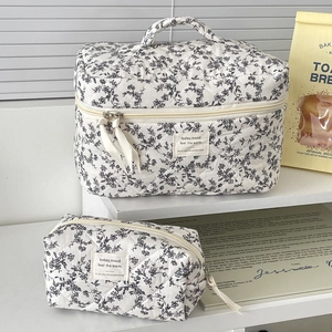 Close-up of two quilted floral toiletry bags with black floral patterns on white fabric