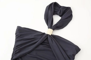 Détail d'une robe dos nu noire élégante avec tissu froncé et boucle en métal doré