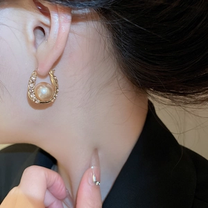 Detailed view of U-shaped champagne pearl earrings with sparkling diamond pavé crystals