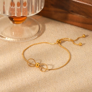 Détail du bracelet nœud doré avec chaîne serpent réglable sur un fond en lin naturel