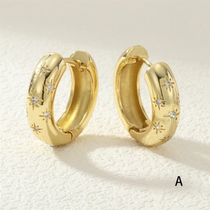 Détail de boucles d'oreilles créoles dorées avec motifs d'étoiles et zircons blancs