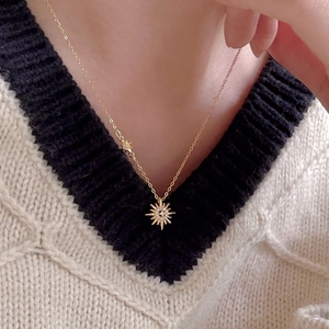 Close-up of a gold starburst necklace with zircon stones on a knitted sweater
