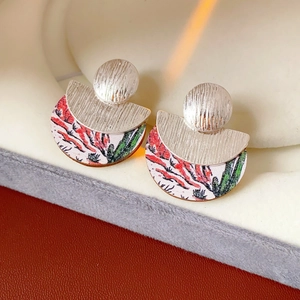 Detail of round wooden earrings with red-green artistic pattern and textured silver-tone metal