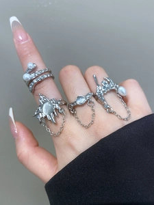 Detailed view of silver bow rings set with pearls and cat eye stones on fingers