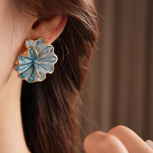 Detail of vintage flower stud earring with blue enamel and crystals on a model's ear
