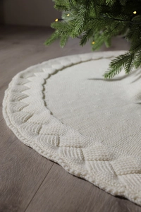 Close-up of white cable knit Christmas tree skirt showing detailed texture and patterns