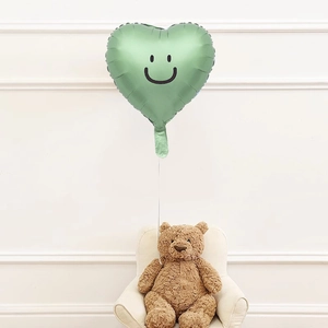 Close-up of a green heart-shaped smiley face balloon for festive party scene decoration