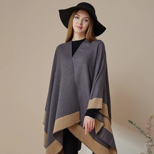 Elegant grey knit poncho with camel trim and striped borders for a chic layered look