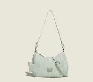 Detail of mint green underarm bag with butterfly charm and pleated fabric texture