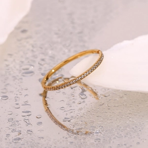 Macro detail of 18K gold plated bangle with micro-pave zircons on a wet surface