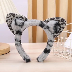 Close-up of plush grey leopard print cat ear headband on a minimalist wooden surface
