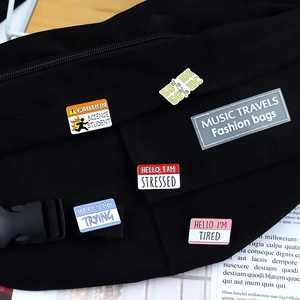 Funny speech bubble enamel pins with witty English slogans on a black canvas bag