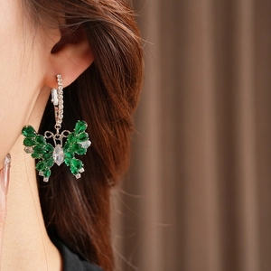 Macro shot of butterfly earrings with green stones and sparkling zircon crystals