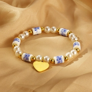 Détail du bracelet avec perles blanches, perles florales et breloque coeur dorée