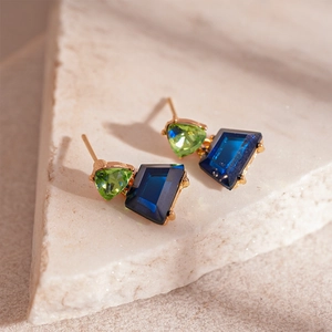 Detailed close-up of geometric earrings with green triangle and blue trapezoid stones