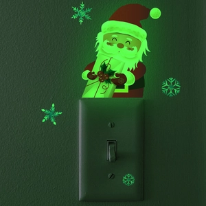Luminous Santa Claus switch sticker glowing in dark on wall with snowflake detail