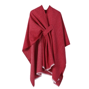 Detailed close-up of a red knit poncho wrap featuring elegant white tassel trim details