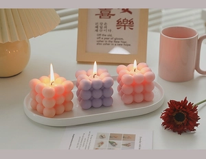 Detailed view of bubble cube scented candles in pink and purple on a white tray
